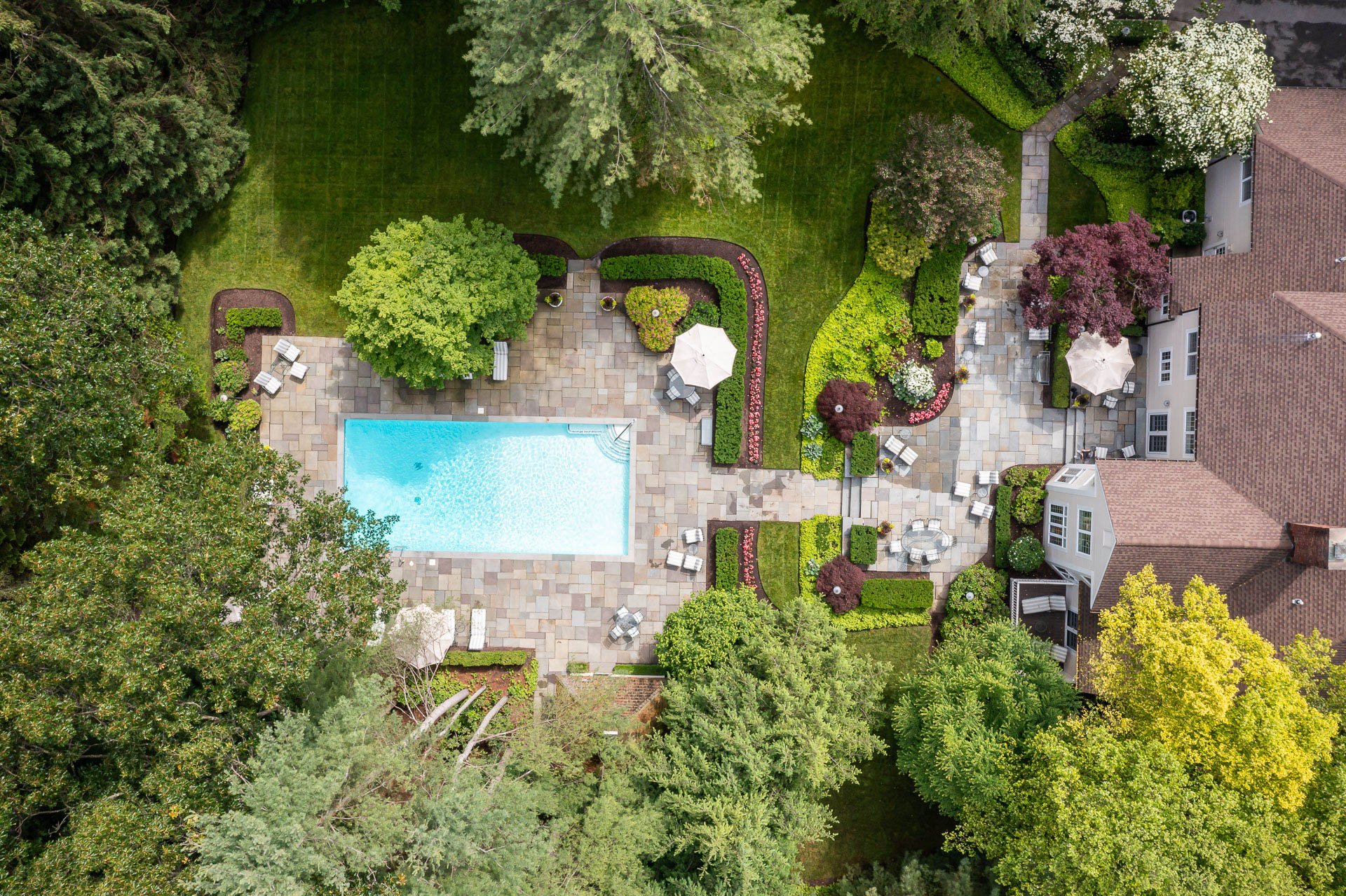 full landscape seen from the air with a pool, patio, paths, and planting