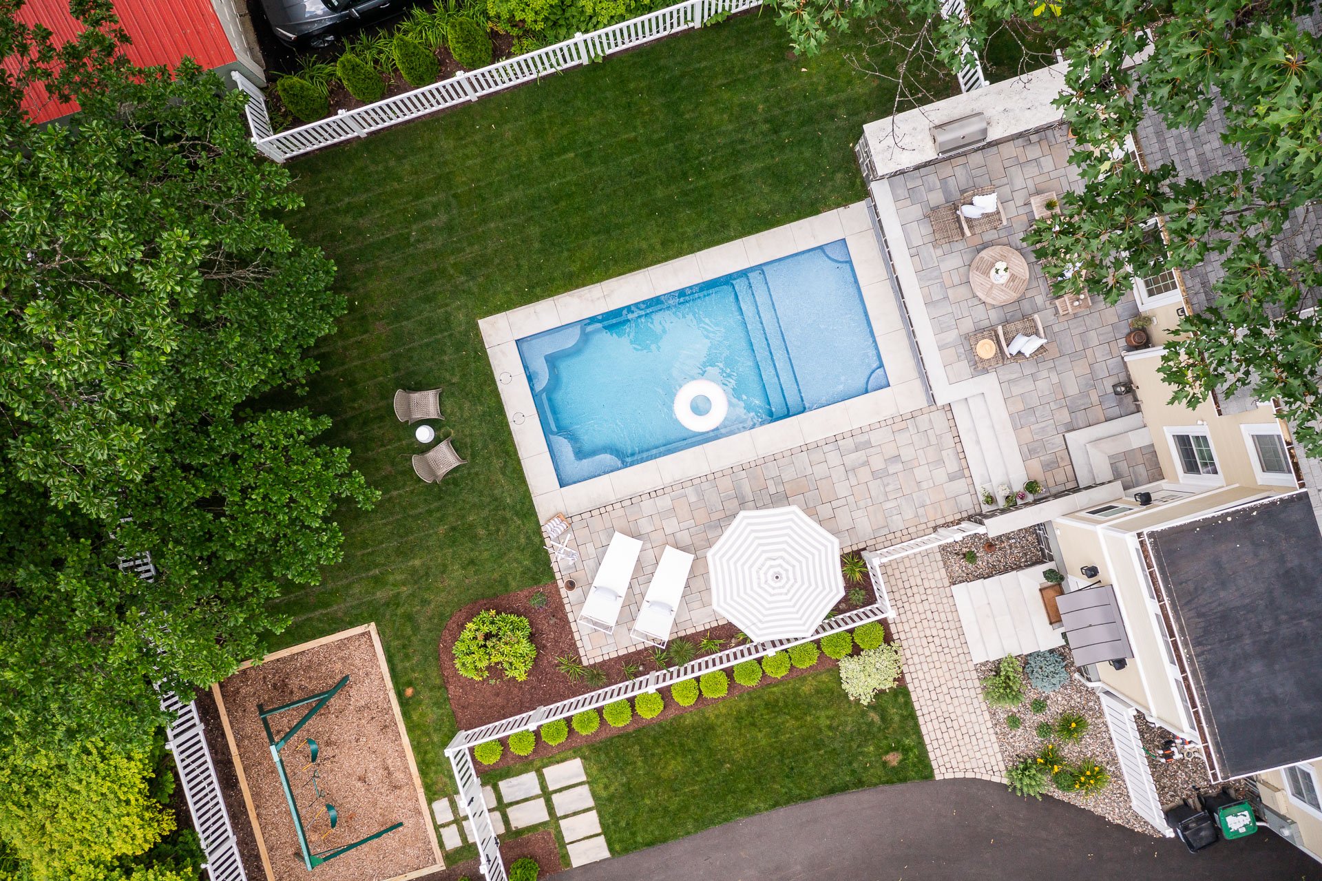 aerial view of a pool with a concrete border and paver patio