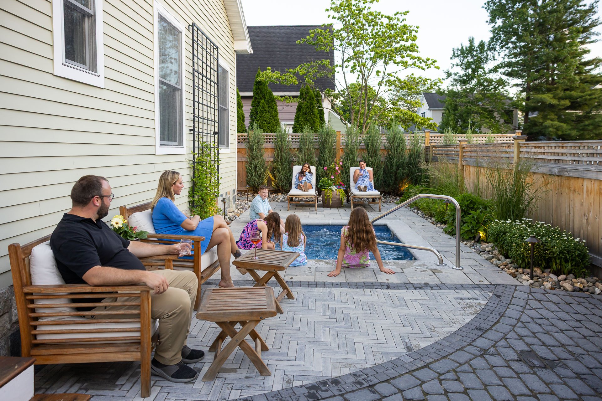 family sitting by the pool in a small backyard
