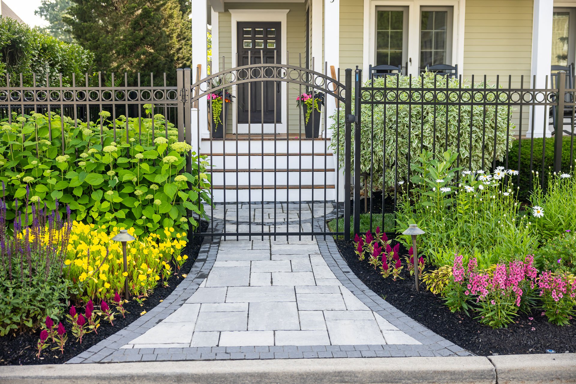 front entry flanked by planting beds full of colorful flowers
