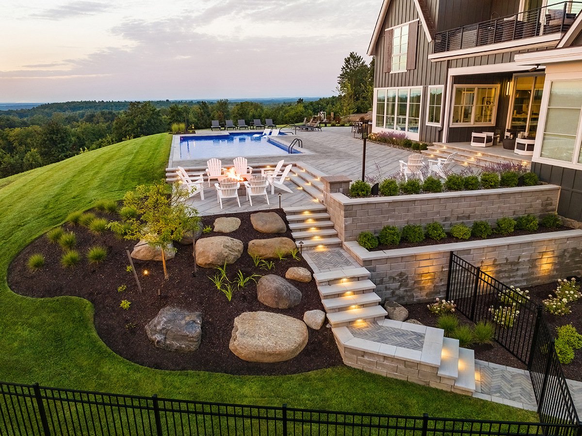 aerial steps planting beds boulders lighting paver walkway patio fire pit seating walls shrubs pool ohannlon