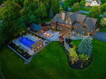 aerial view of a full scope landscape project with a pool, pergola, fire pit, and multiple patios