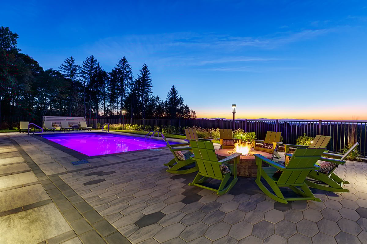 pool with color-changing led lights and a firepit seating area