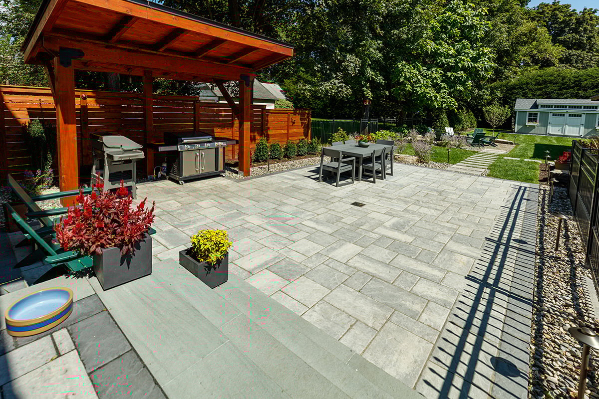 stone patio complete grill pergola, seating, and pathways to the rest of the yard