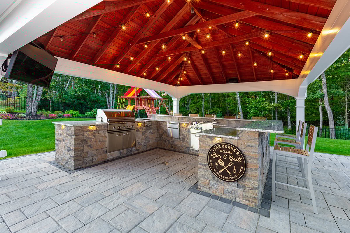 a custom u-shaped outdoor kitchen with lighting, television, and appliances