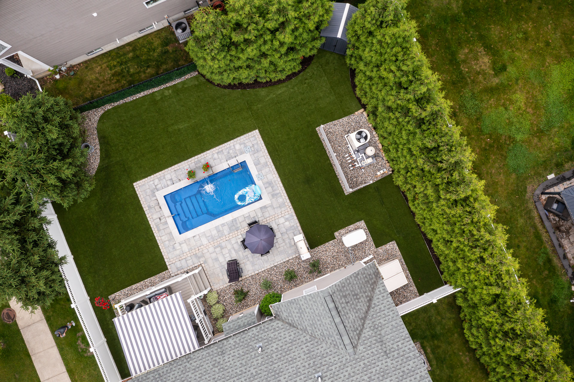https://241926021.fs1.hubspotusercontent-na2.net/hubfs/241926021/Images/2025%20Photo%20Shoot%20-%20Renamed/aerial%20top%20down%20small%20pool%20backyard%20arborvitae%20screening%20privacy%20shed%20synthetic%20turf%20gravel%20beds%20grill%20patio%20deck%20chairs%20awning%20mike%203.jpg